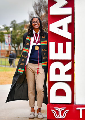 Delainee Gibson standing next to a DREAM twu sign