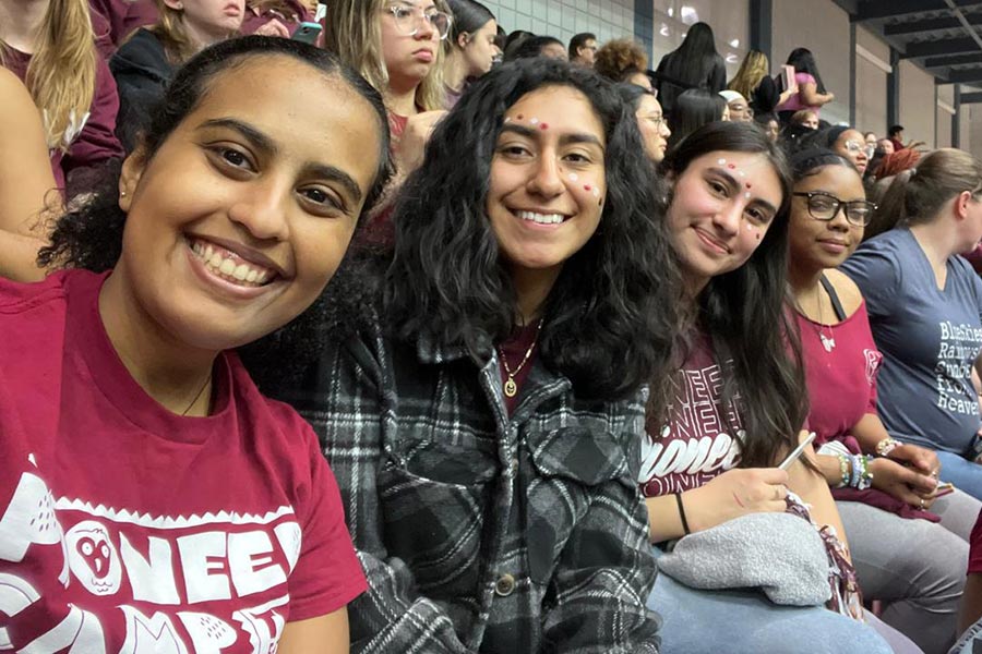 a group of four business students sit at a basketball game 