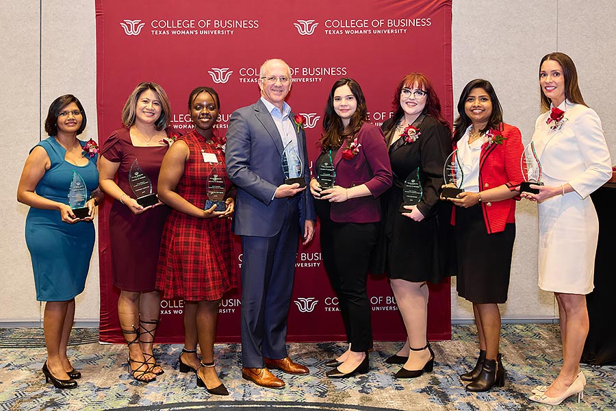 a group of eight people stand in front of COB backdrop holding awards