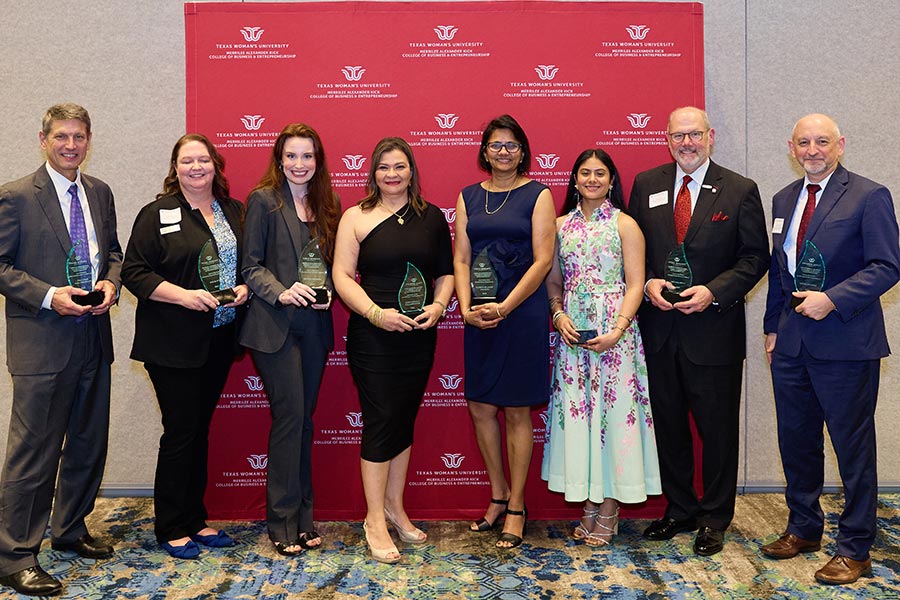 eight award winners from Best in Business banquet stand in front of MAK College backdrop