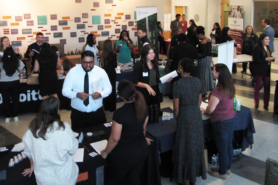 groups of students interact with professionals at tables at student development event 