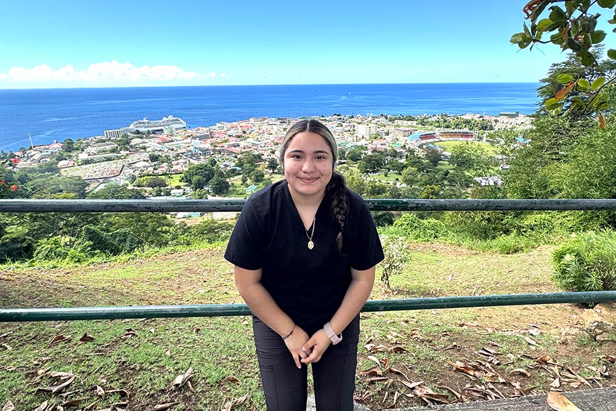 a TWU student stands in front of a fence overlooking an island