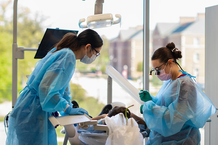 two dental hygiene students give a dental cleaning to a child in the dental hygiene clinic