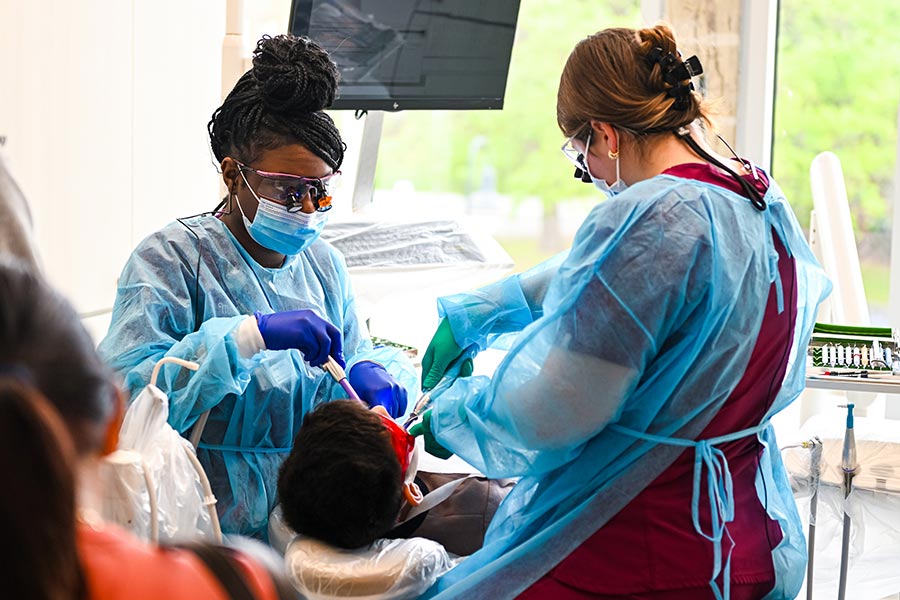 two TWU dental hygiene students inspect a patients teeth