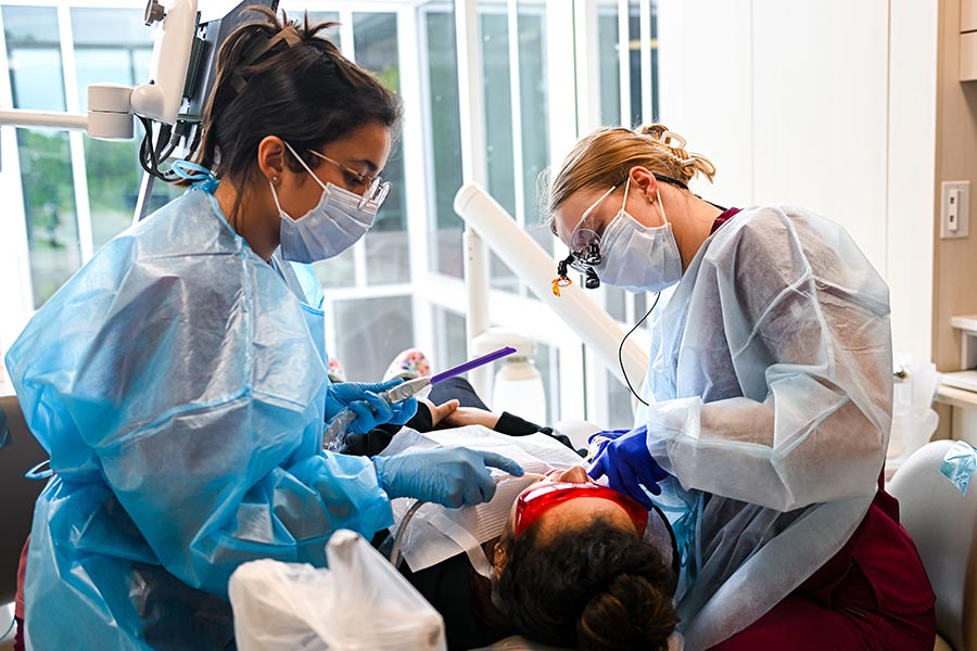 two TWU dental hygiene students inspect a patients teeth