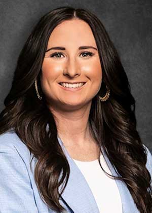 Haley Colwell in white hat and gray t-shirt stands next to softball player in batting helmet