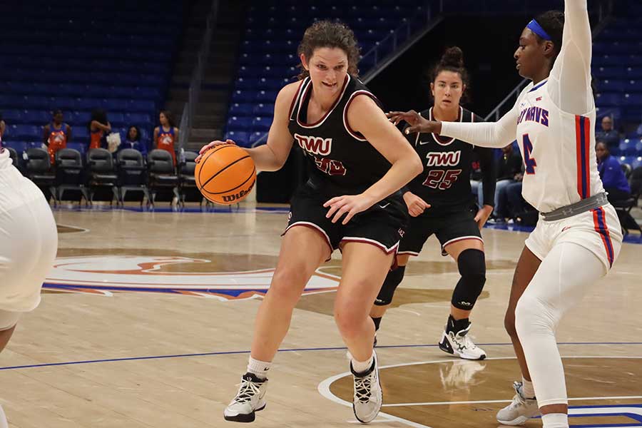 TWU basketball player dribbles ball during game