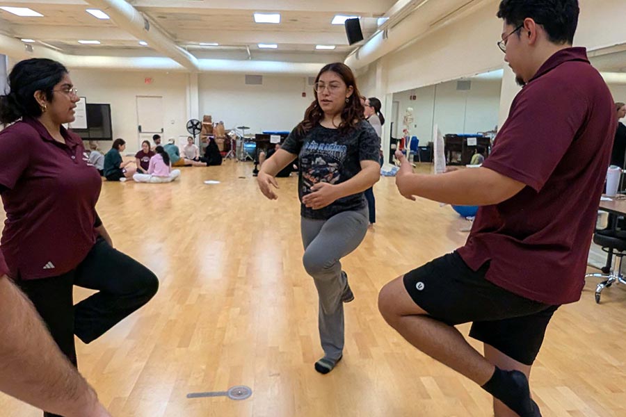a dance student demonstrates a dance movement to three other students