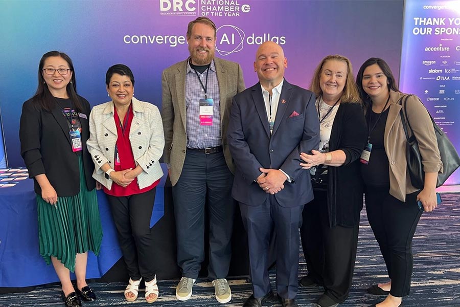 five COB faculty and staff members stand in front of purple backdrop