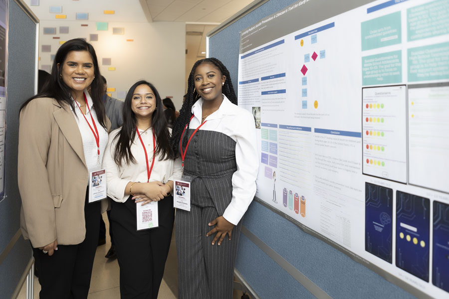 Poster presenters pose with poster at Doswell Health Informatics Conference