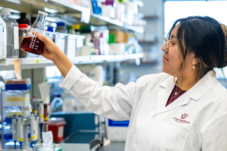 Three TWU students prep to begin cooking in an industrial kitchen setting.
