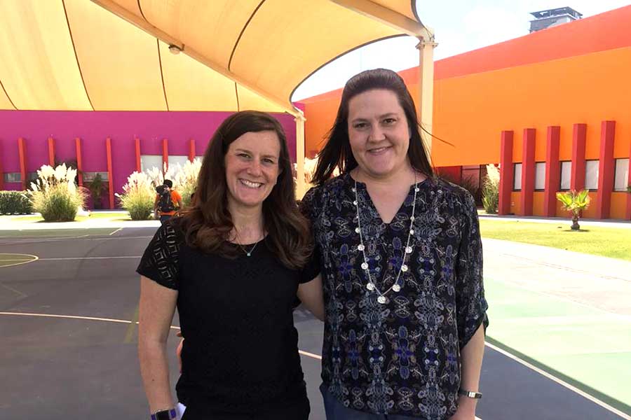 two women stand next to one another under umbrella